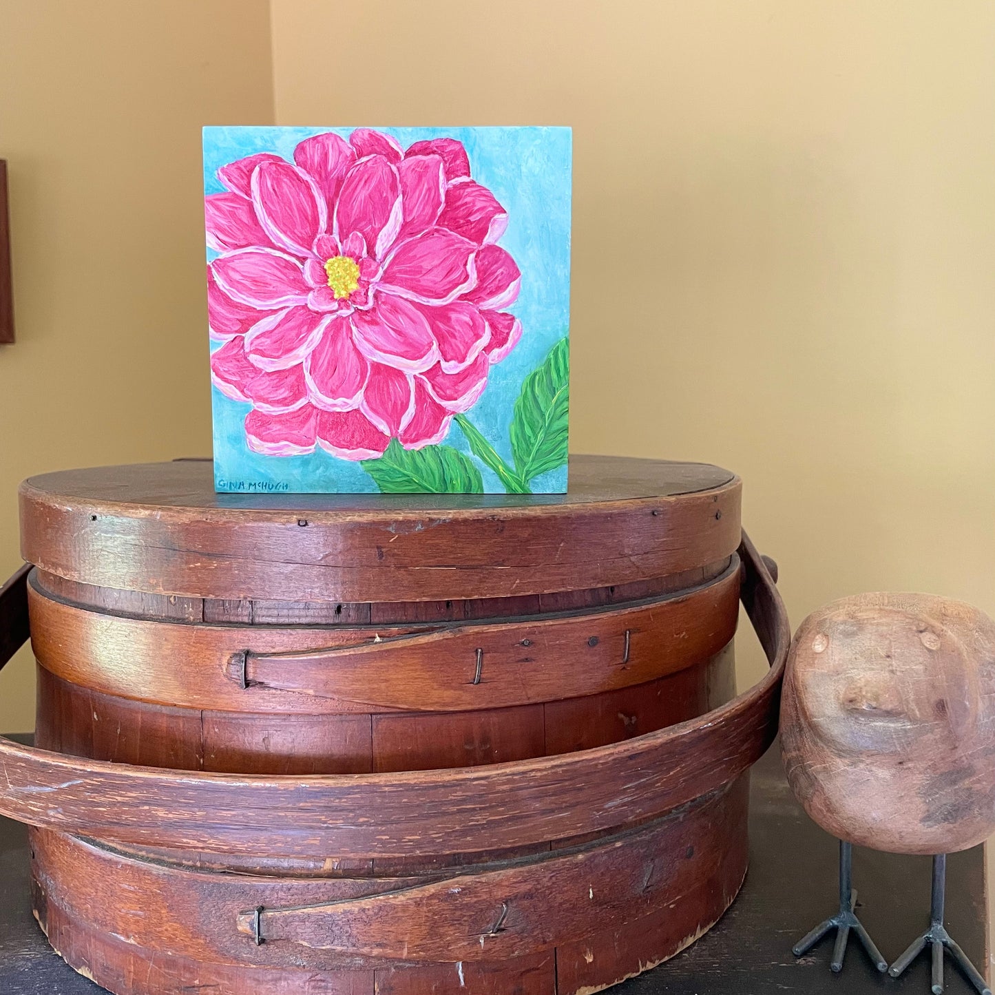 Painting of a pink dahlia flower on a cradled wood panel on a mantle