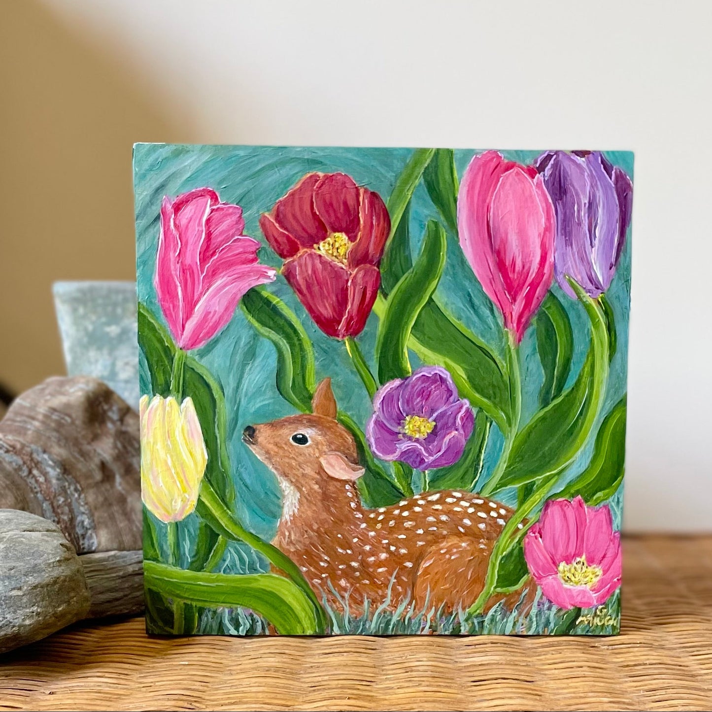Painting of a fawn lying in a bed of multi color tulips swaying in the wind