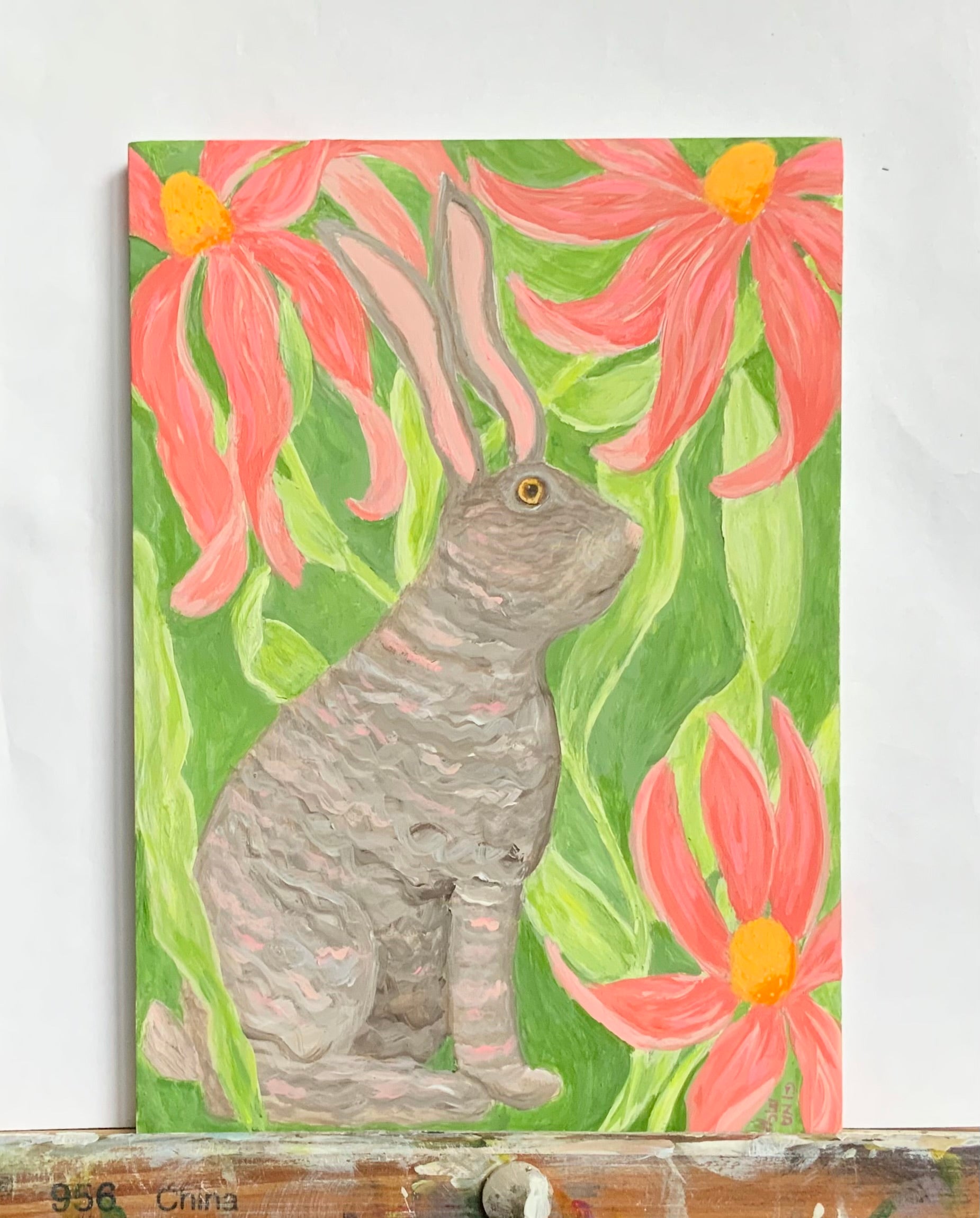 Painting of rabbit with long ears among pink flowers on a green background