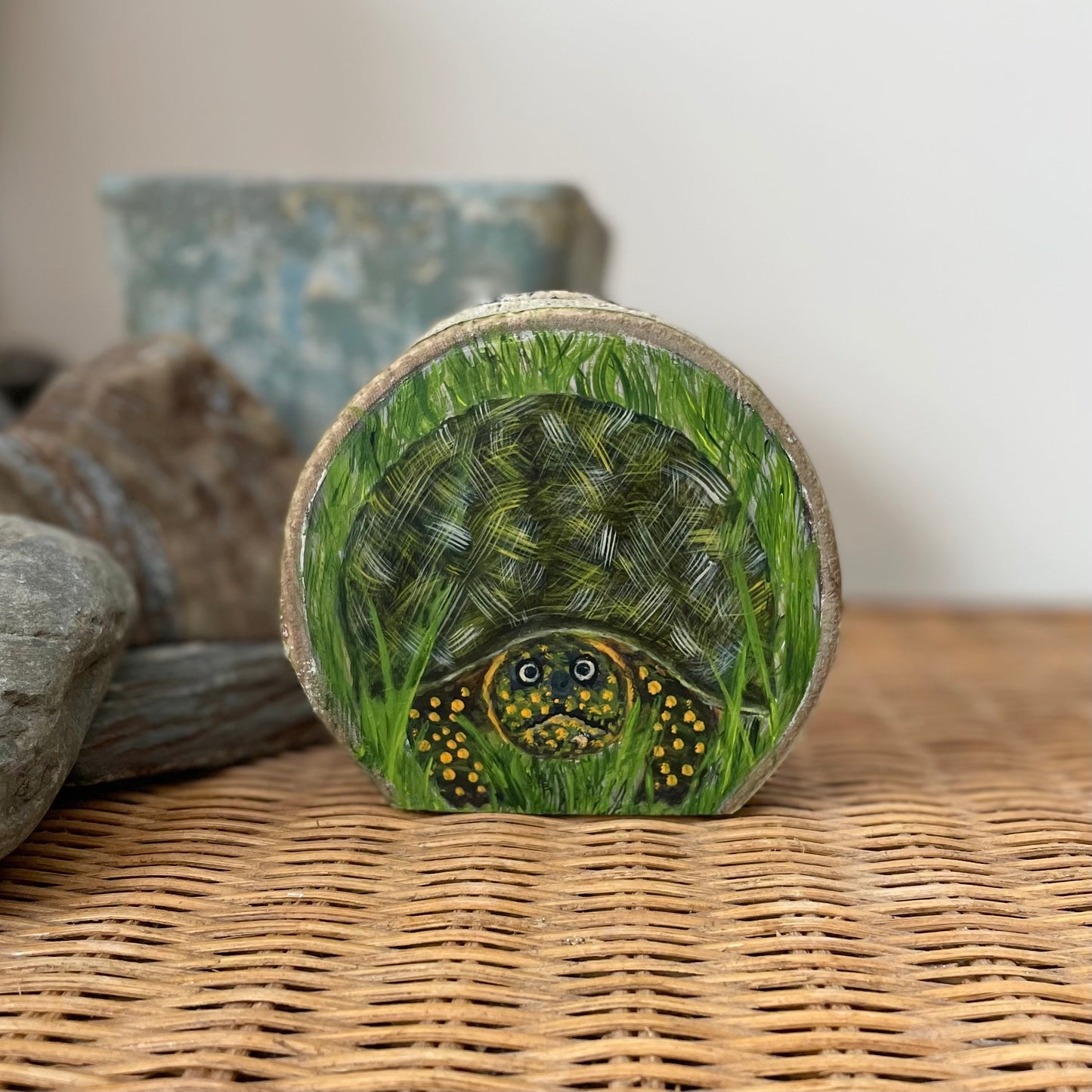 Painting of a wood turtle in the grass on an aspen wood slice with bark framing the outer edge