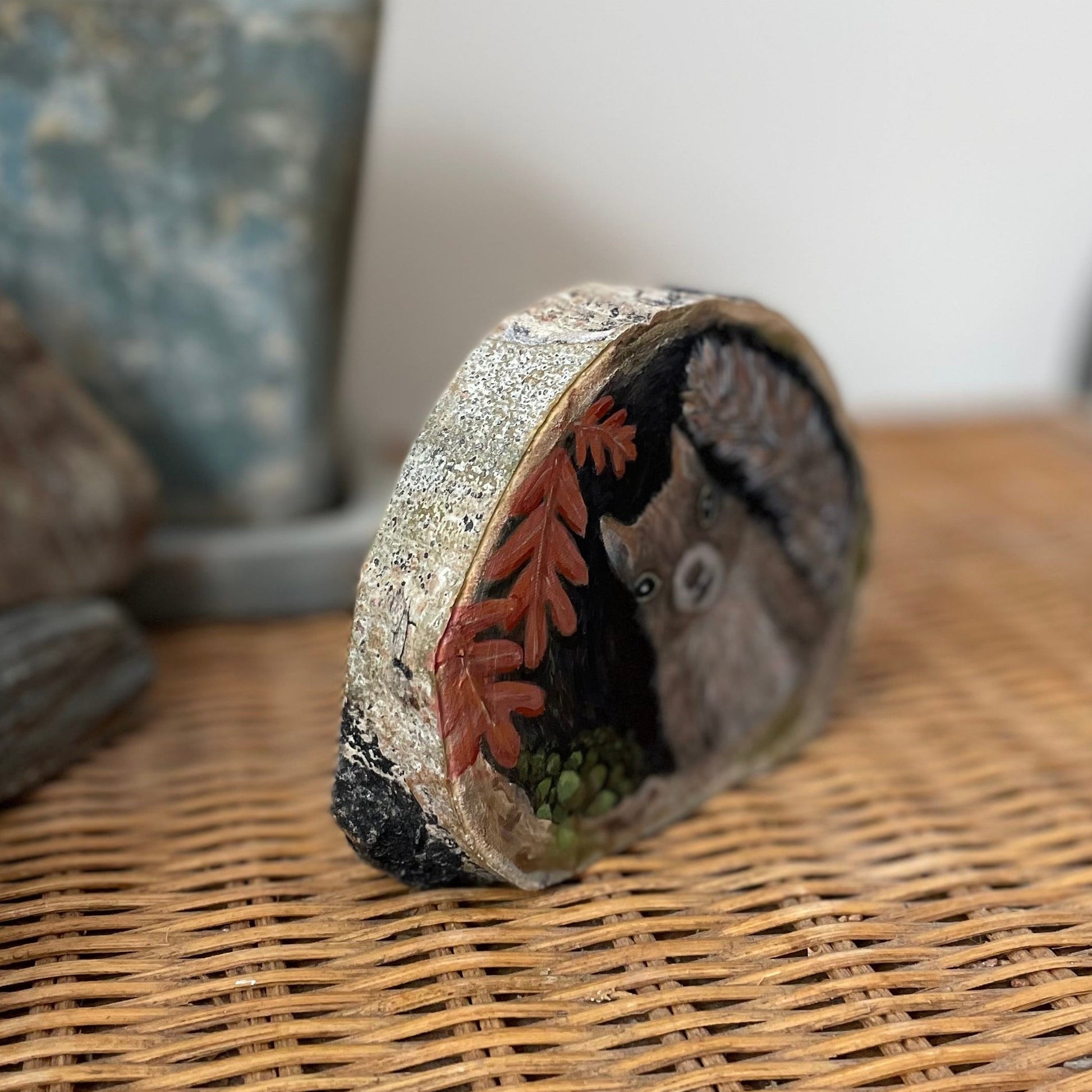 Painting of a squirrel nesting in a tree cavity with acorns and oak leaves on a freestanding aspen wood slice
