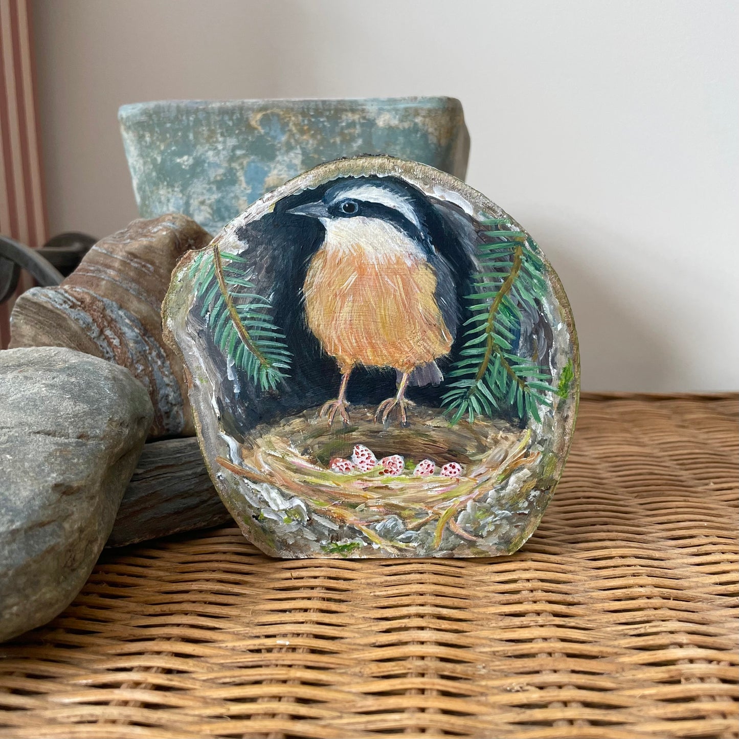 Painting of a Red-breasted Nuthatch on a next inside a tree cavity with pine branches on a freestanding aspen wood slice