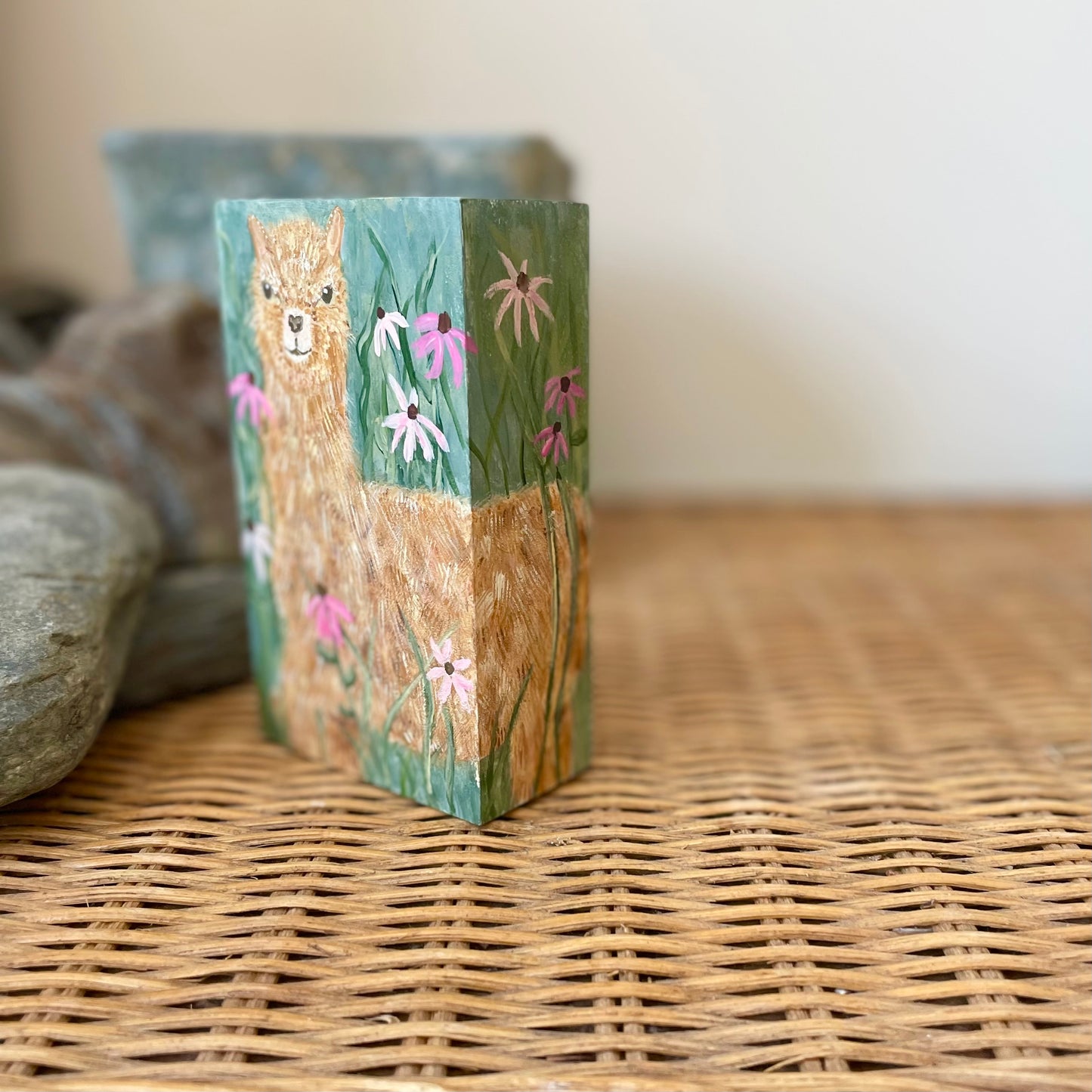 Small rectangular painting of a young alpaca in a field of flowers