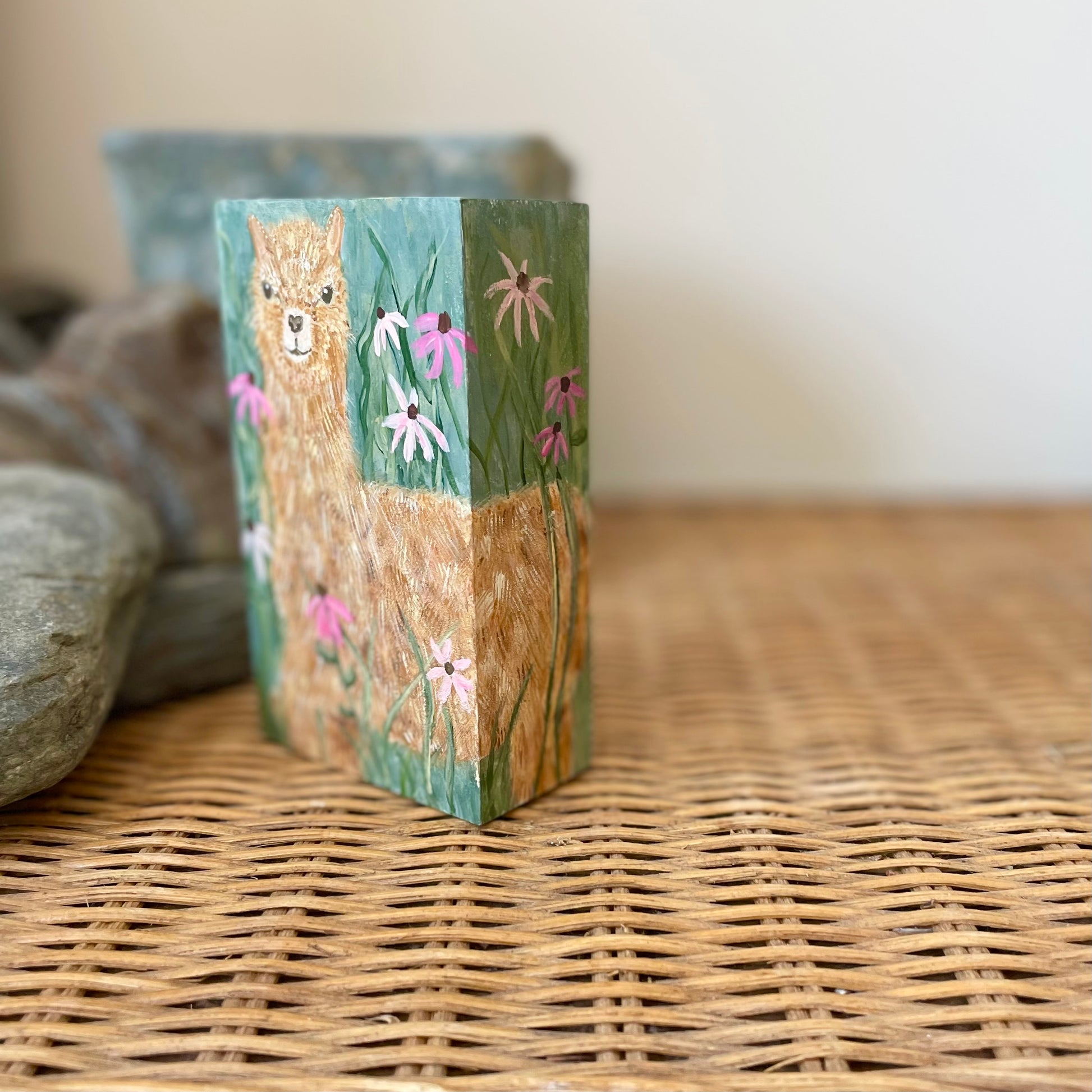 Small rectangular painting of a young alpaca in a field of flowers