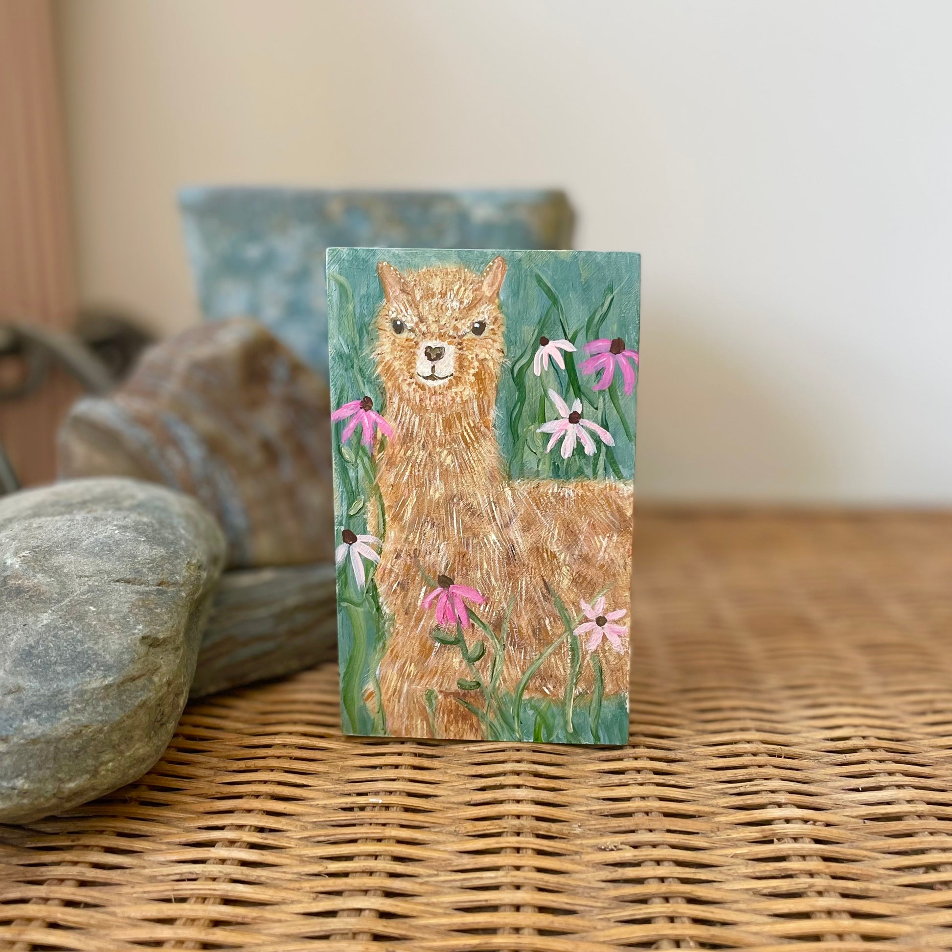 Small rectangular painting of a young alpaca in a field of flowers