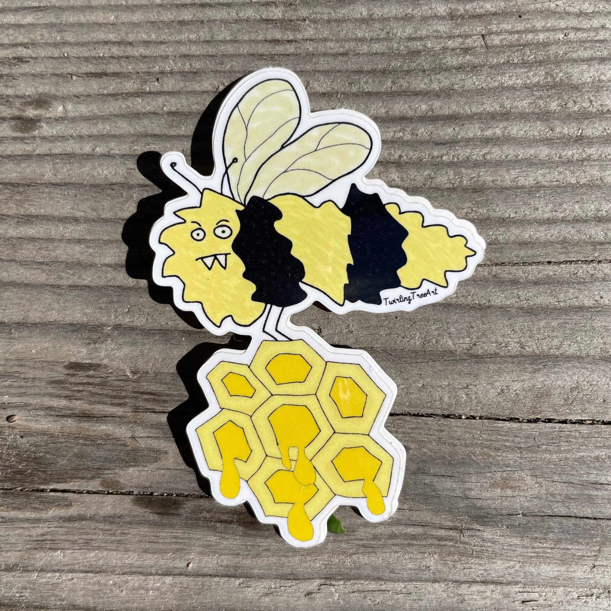 Fun sticker of a yellow and black striped angry bee carrying a honeycomb