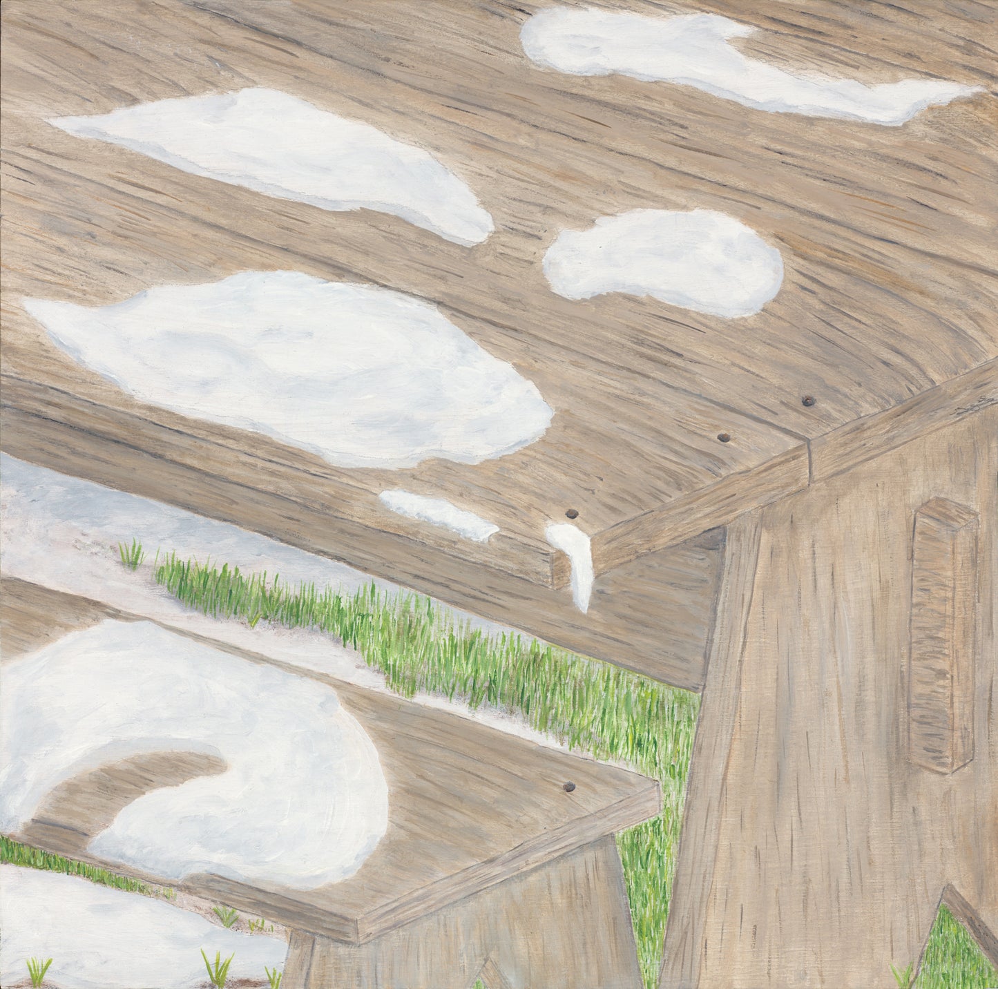 Weathered wood table with melting snow and emerging spring green grass 